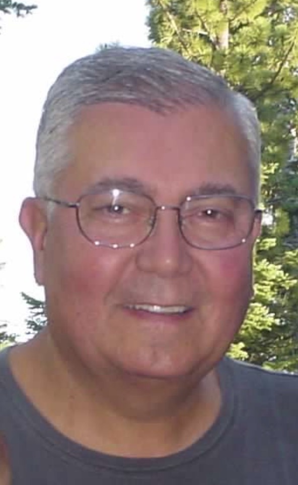 Patrick P. Randazzo, smiling outdoors in front of pine trees
